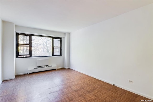 empty room featuring a baseboard heating unit and parquet floors