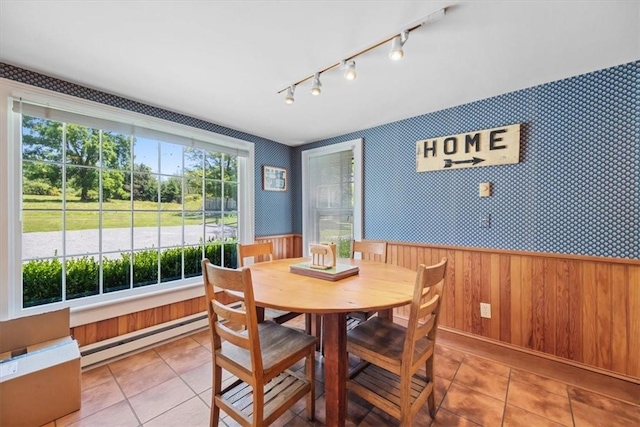 tiled dining area featuring a baseboard heating unit and wood walls