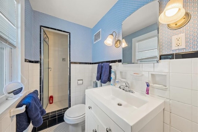 bathroom featuring vanity, a shower with door, toilet, and tile walls