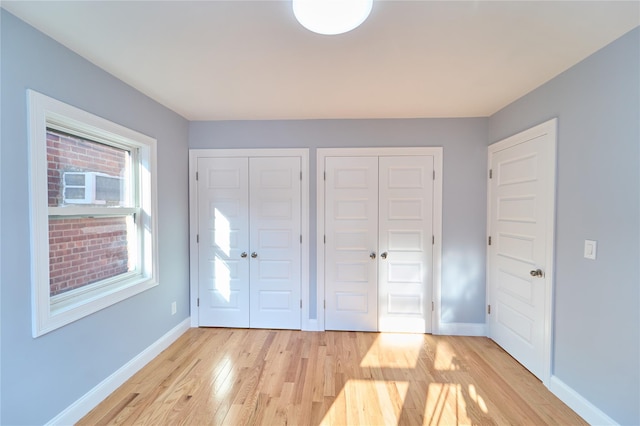 unfurnished bedroom featuring light hardwood / wood-style floors and two closets