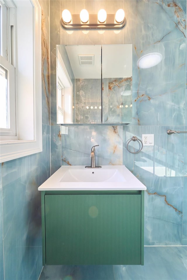 bathroom featuring vanity, tasteful backsplash, and tile walls