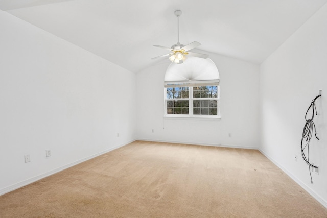 carpeted spare room with ceiling fan and vaulted ceiling