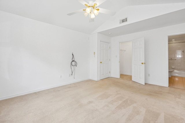 unfurnished bedroom with ensuite bathroom, ceiling fan, light colored carpet, and vaulted ceiling