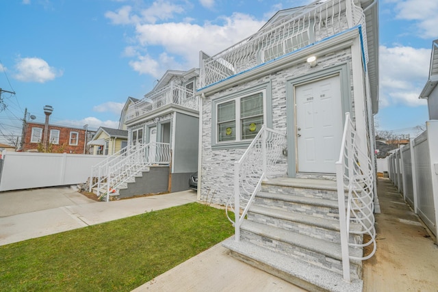 view of front of house with a balcony, a front lawn, and a patio area