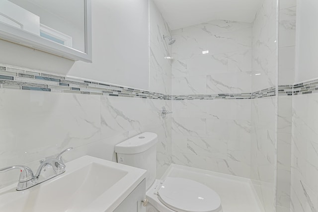 bathroom with tiled shower, toilet, tile walls, and vanity