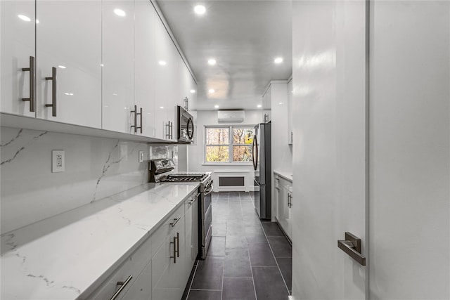 kitchen with light stone countertops, white cabinetry, stainless steel appliances, and a wall unit AC