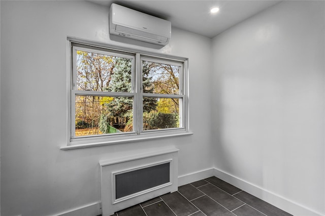 unfurnished room with dark tile patterned floors, a wall unit AC, and a wealth of natural light