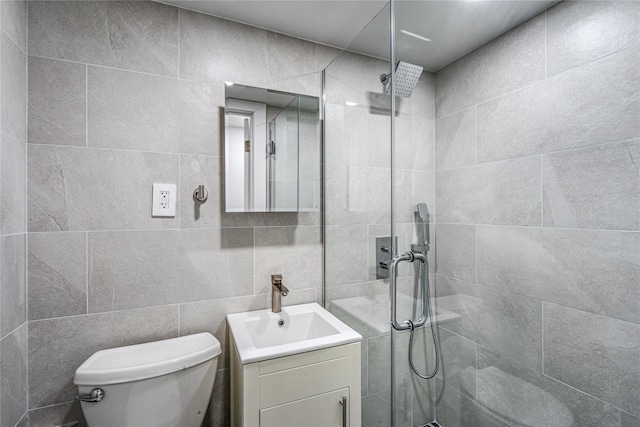 bathroom featuring vanity, toilet, tiled shower, and tile walls