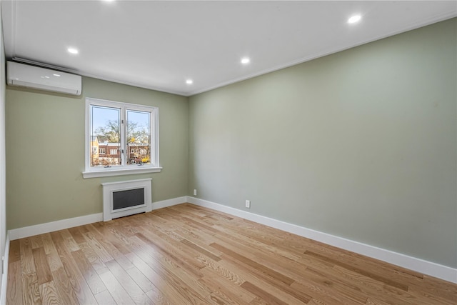 unfurnished room with light wood-type flooring and a wall unit AC