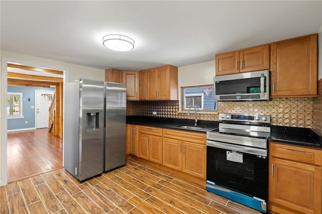 kitchen with light wood-type flooring, stainless steel appliances, backsplash, and sink