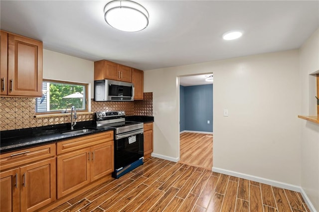 kitchen with sink, tasteful backsplash, dark hardwood / wood-style floors, dark stone counters, and electric stove