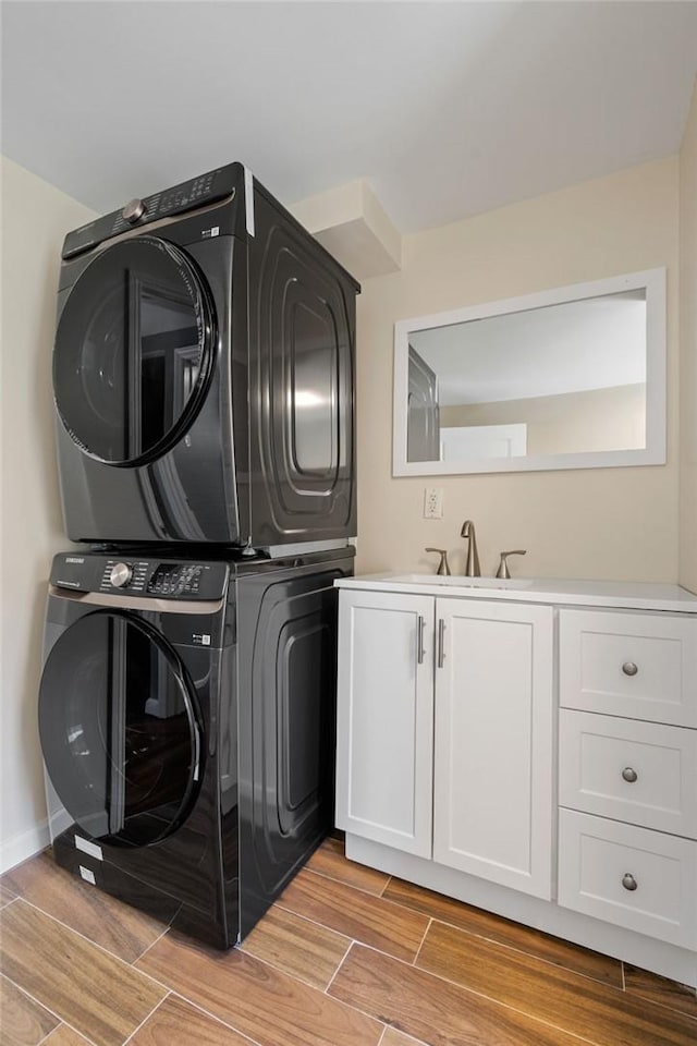 laundry area with sink, cabinets, and stacked washer / drying machine