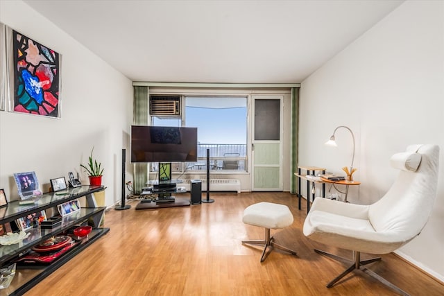 living area with hardwood / wood-style floors and an AC wall unit