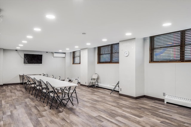 dining space with a wall mounted air conditioner and light hardwood / wood-style floors