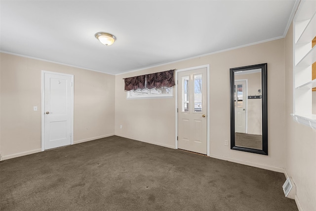 spare room featuring ornamental molding and dark carpet