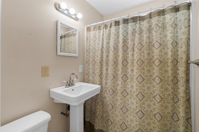 bathroom featuring a shower with curtain, toilet, and sink