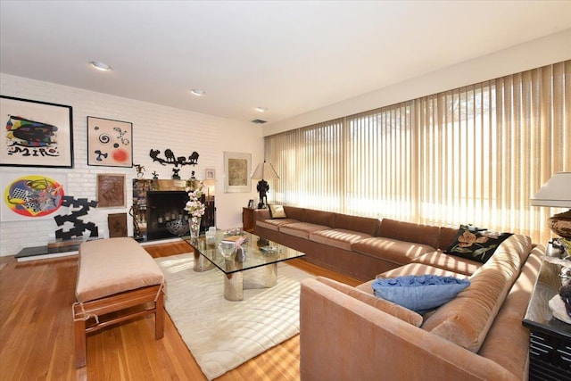 living room with light hardwood / wood-style flooring and brick wall