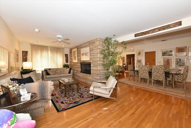 living room featuring a fireplace, ceiling fan, and light hardwood / wood-style flooring