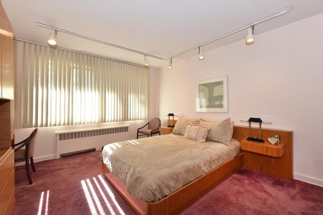 bedroom with dark colored carpet, radiator heating unit, and rail lighting