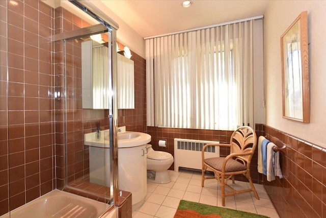 bathroom with tile patterned floors, radiator, a wealth of natural light, and tile walls