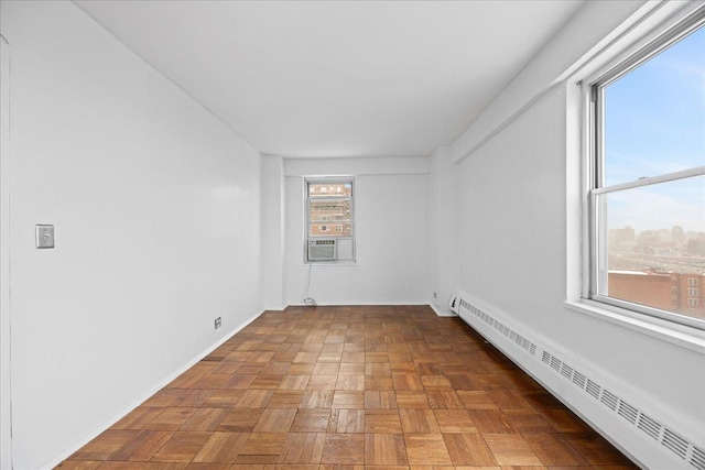 unfurnished room with cooling unit, a wealth of natural light, parquet flooring, and a baseboard heating unit