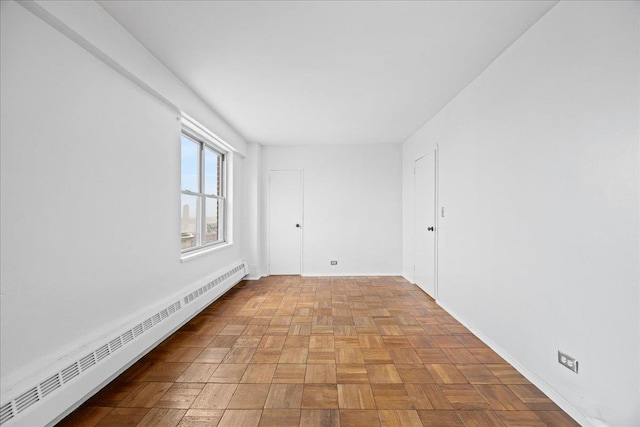 empty room with light parquet floors and a baseboard heating unit