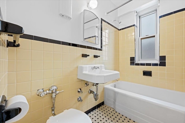 full bathroom with tile patterned floors, tiled shower / bath combo, sink, tile walls, and toilet