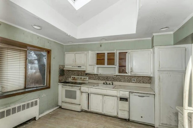 kitchen with white cabinetry, white appliances, radiator heating unit, and sink