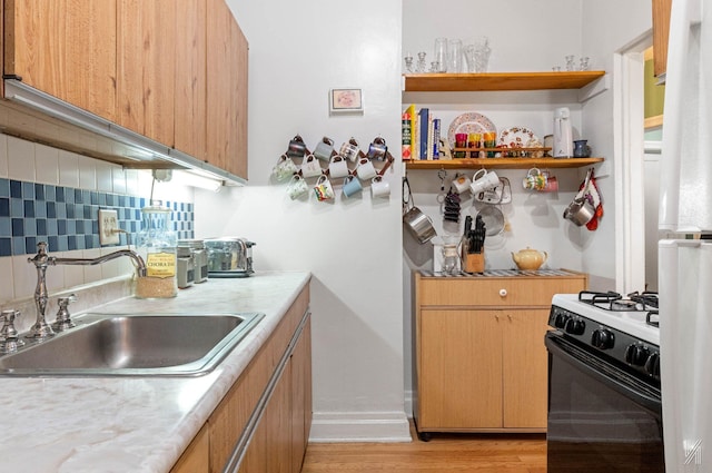 kitchen with black gas range, tasteful backsplash, sink, and light hardwood / wood-style floors