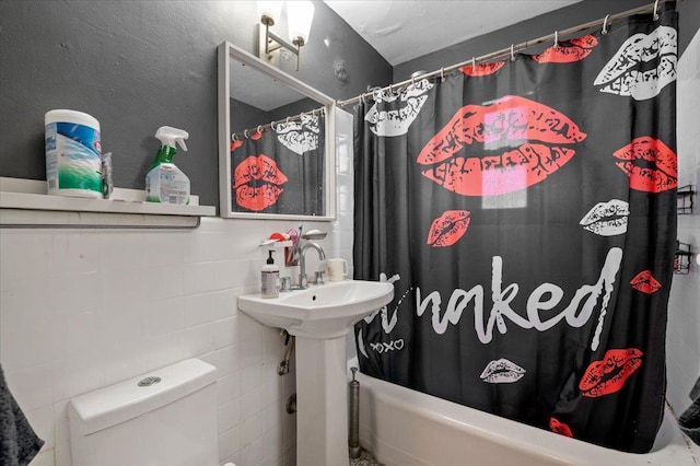 bathroom featuring shower / bath combo, toilet, and tile walls