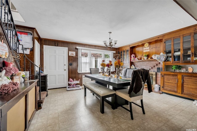 dining space with ornamental molding, radiator heating unit, an inviting chandelier, and wooden walls