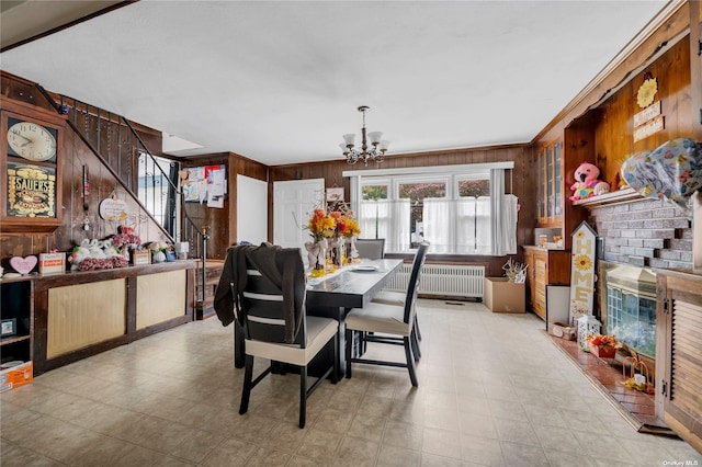 dining area featuring radiator heating unit, ornamental molding, wooden walls, and an inviting chandelier