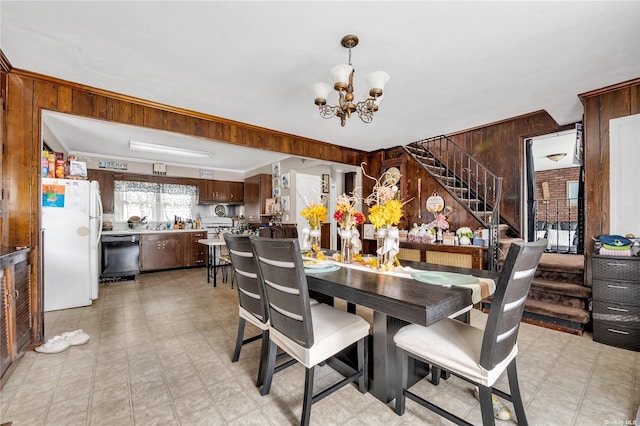 dining room featuring ornamental molding, a notable chandelier, and wood walls