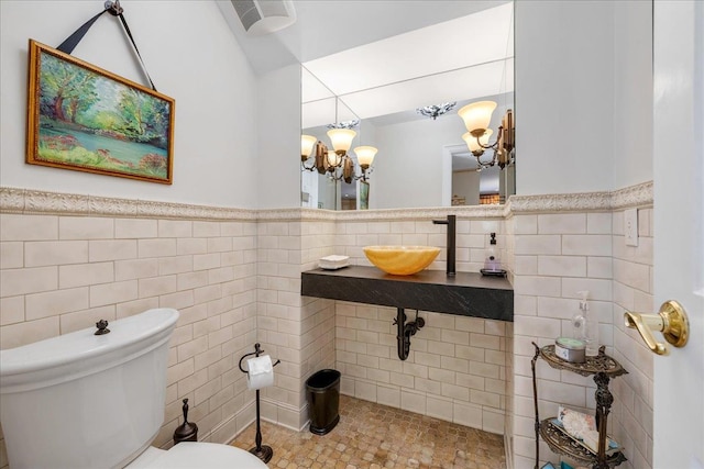 bathroom featuring sink, tile walls, an inviting chandelier, tile patterned floors, and toilet