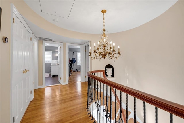 corridor featuring an inviting chandelier and light hardwood / wood-style floors