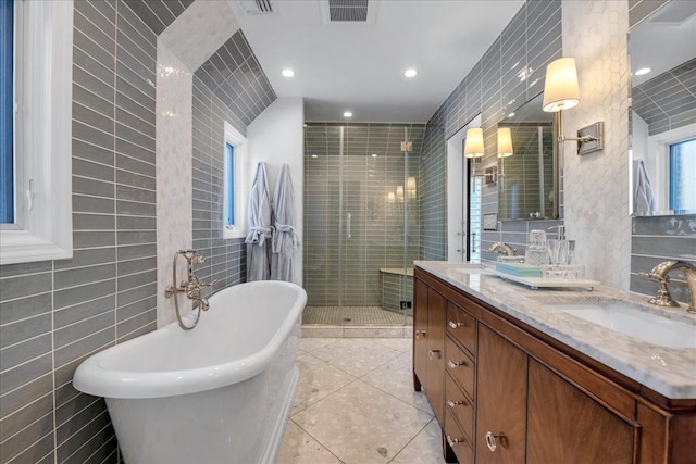 bathroom with independent shower and bath, vanity, tile patterned flooring, and tile walls