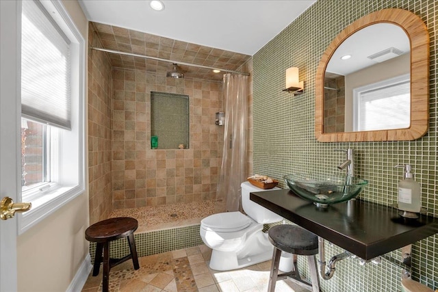 bathroom featuring sink, tile patterned flooring, tasteful backsplash, toilet, and walk in shower