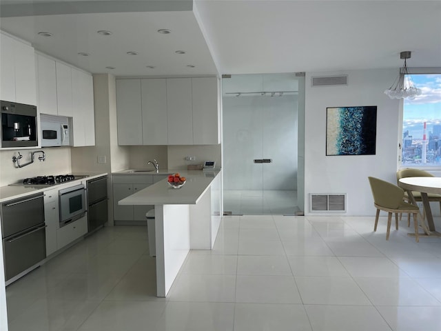 kitchen featuring white cabinets, wall oven, hanging light fixtures, and light tile patterned flooring