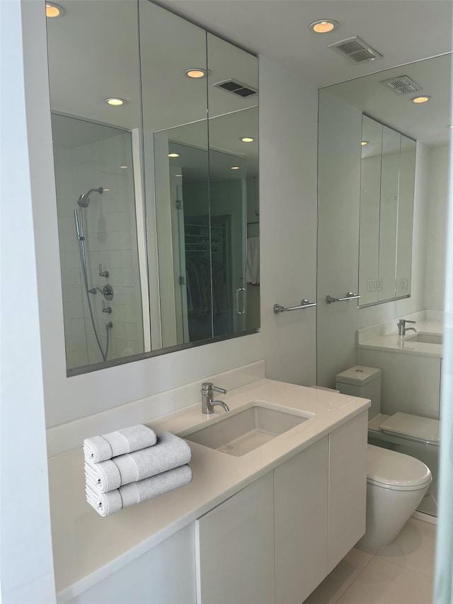 bathroom featuring tile patterned flooring, vanity, toilet, and tiled shower