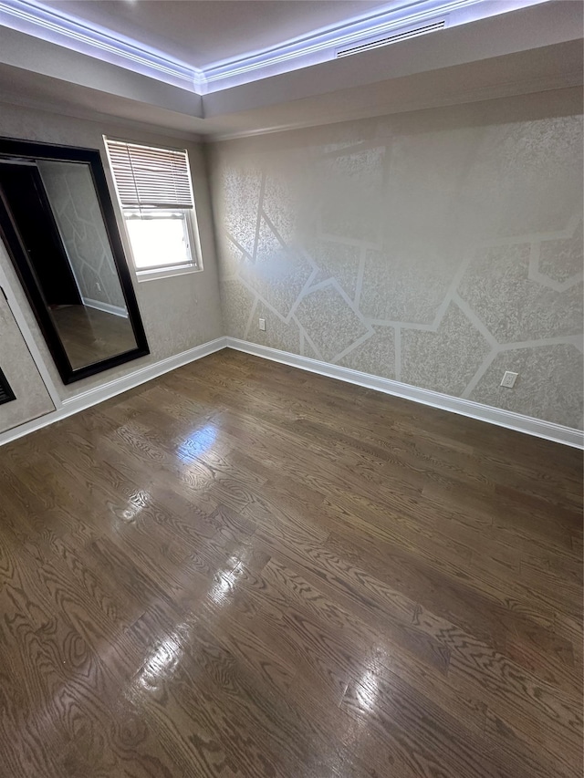 spare room featuring dark wood-type flooring, crown molding, and a premium fireplace