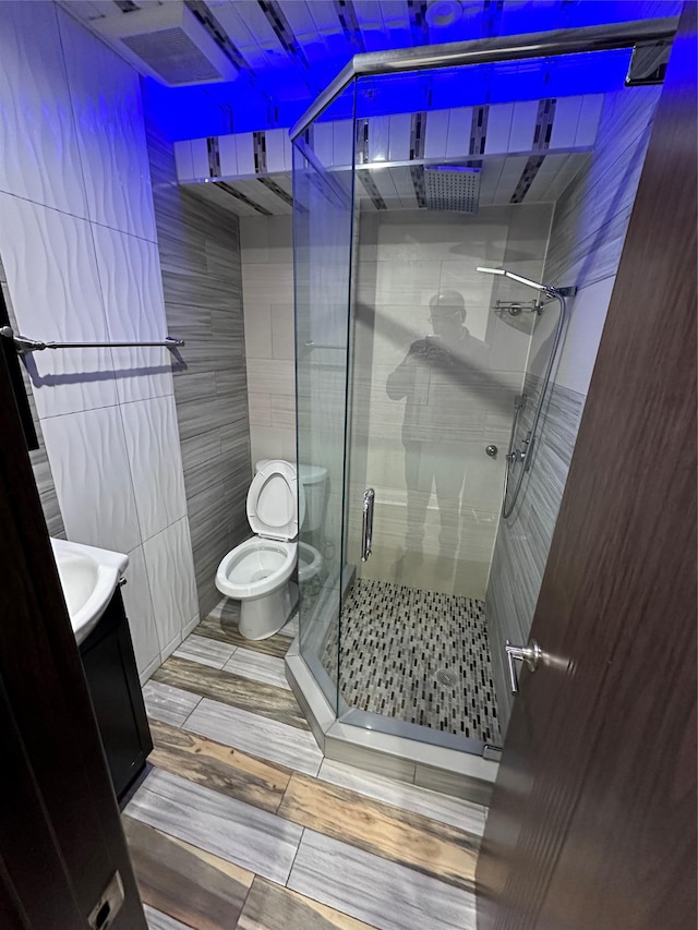 bathroom with tile walls, vanity, an enclosed shower, and toilet