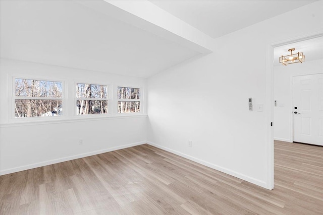 empty room with vaulted ceiling and light hardwood / wood-style floors