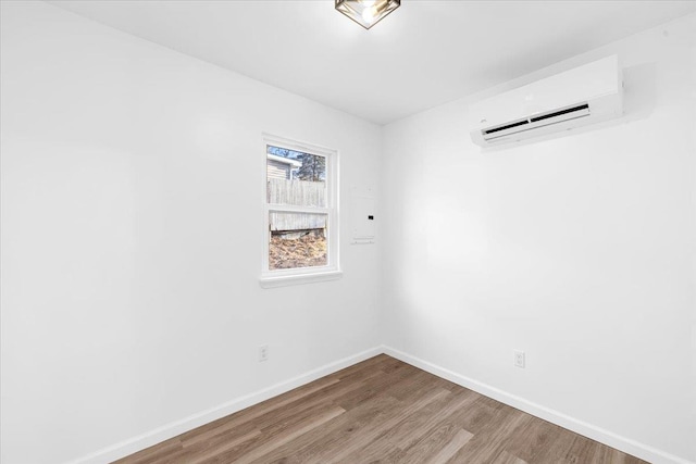 empty room with a wall mounted AC and light hardwood / wood-style flooring