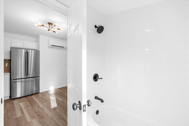 bathroom with wood-type flooring, a wall unit AC, and tiled shower / bath