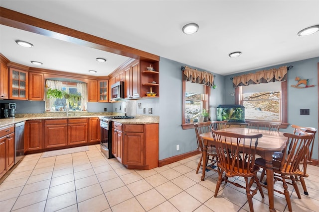 kitchen featuring sink, light stone countertops, stainless steel appliances, and light tile patterned floors