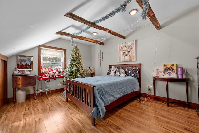 bedroom with lofted ceiling with beams and light hardwood / wood-style floors