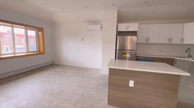 kitchen with white cabinets, sink, stainless steel fridge, a baseboard radiator, and a wall unit AC