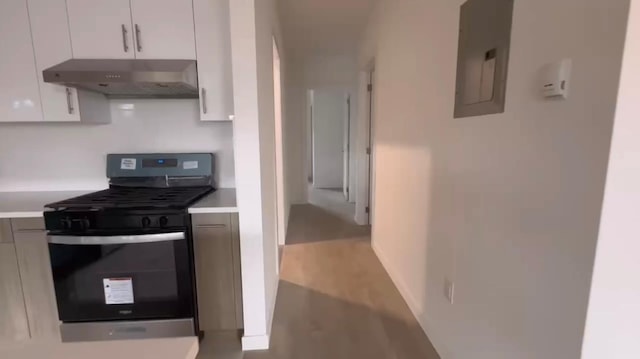 kitchen with electric panel, ventilation hood, wood-type flooring, stainless steel range oven, and white cabinetry