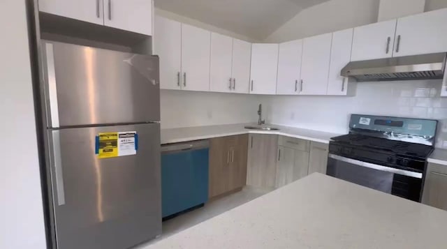 kitchen with appliances with stainless steel finishes, backsplash, vaulted ceiling, sink, and white cabinets