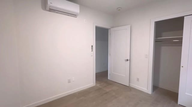 unfurnished bedroom featuring a wall mounted AC and a closet